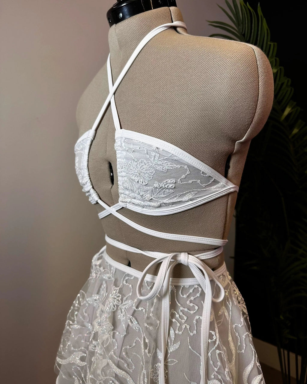Seraphina Wrap Bikini Top in white lace on a mannequin, showcasing its intricate floral pattern and crisscross wrap design for a mesmerizing festival look.