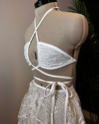 Seraphina Wrap Bikini Top in white lace on a mannequin, showcasing its intricate floral pattern and crisscross wrap design for a mesmerizing festival look.