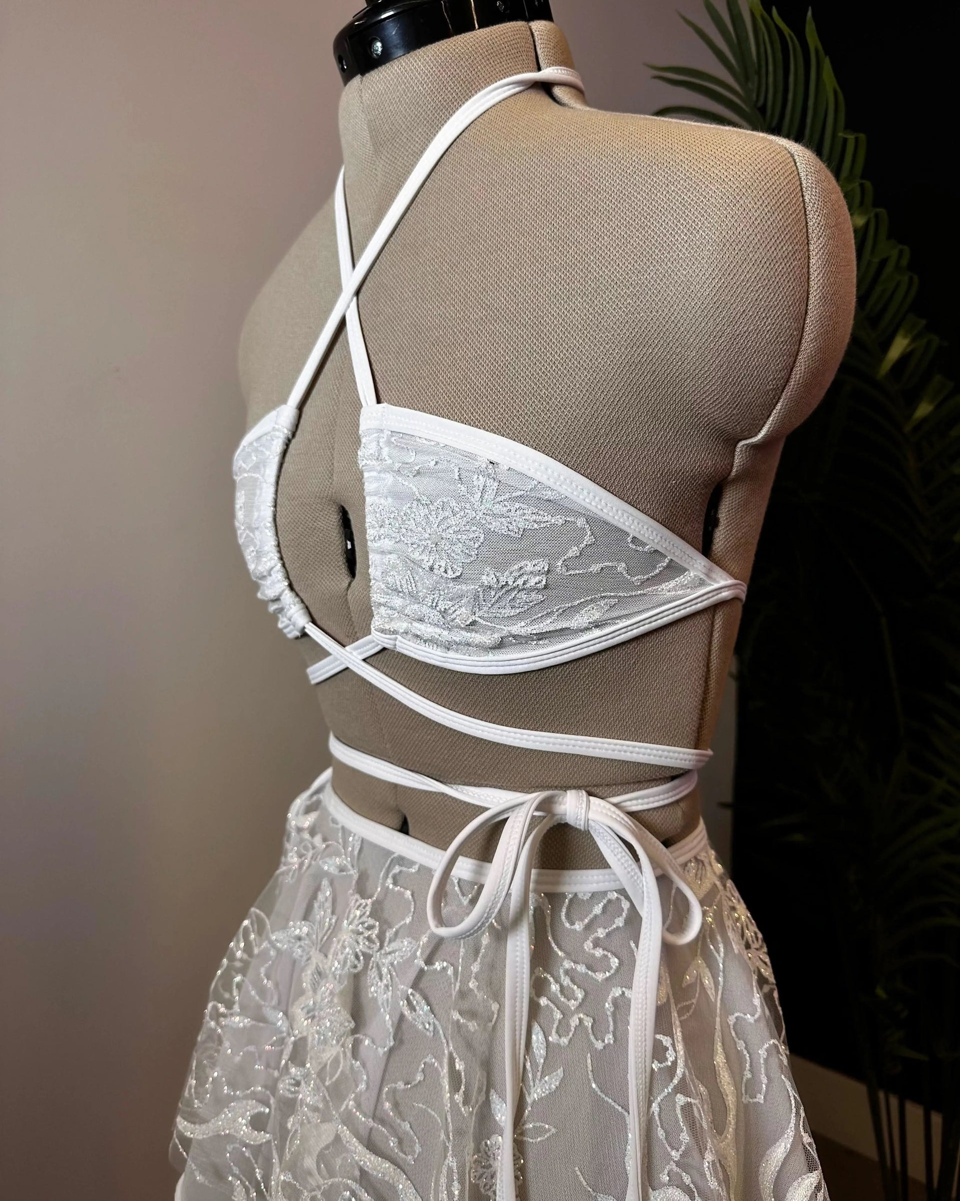 Seraphina Wrap Bikini Top in white lace on a mannequin, showcasing its intricate floral pattern and crisscross wrap design for a mesmerizing festival look.