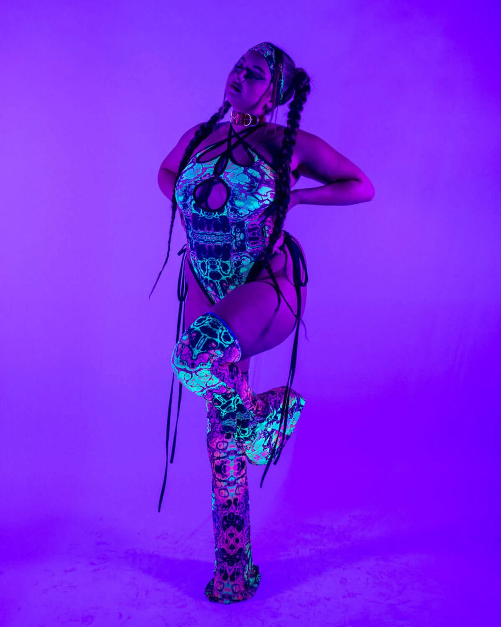 Cross Faded rave bodysuit with skull print and matching leg warmers under purple blacklight