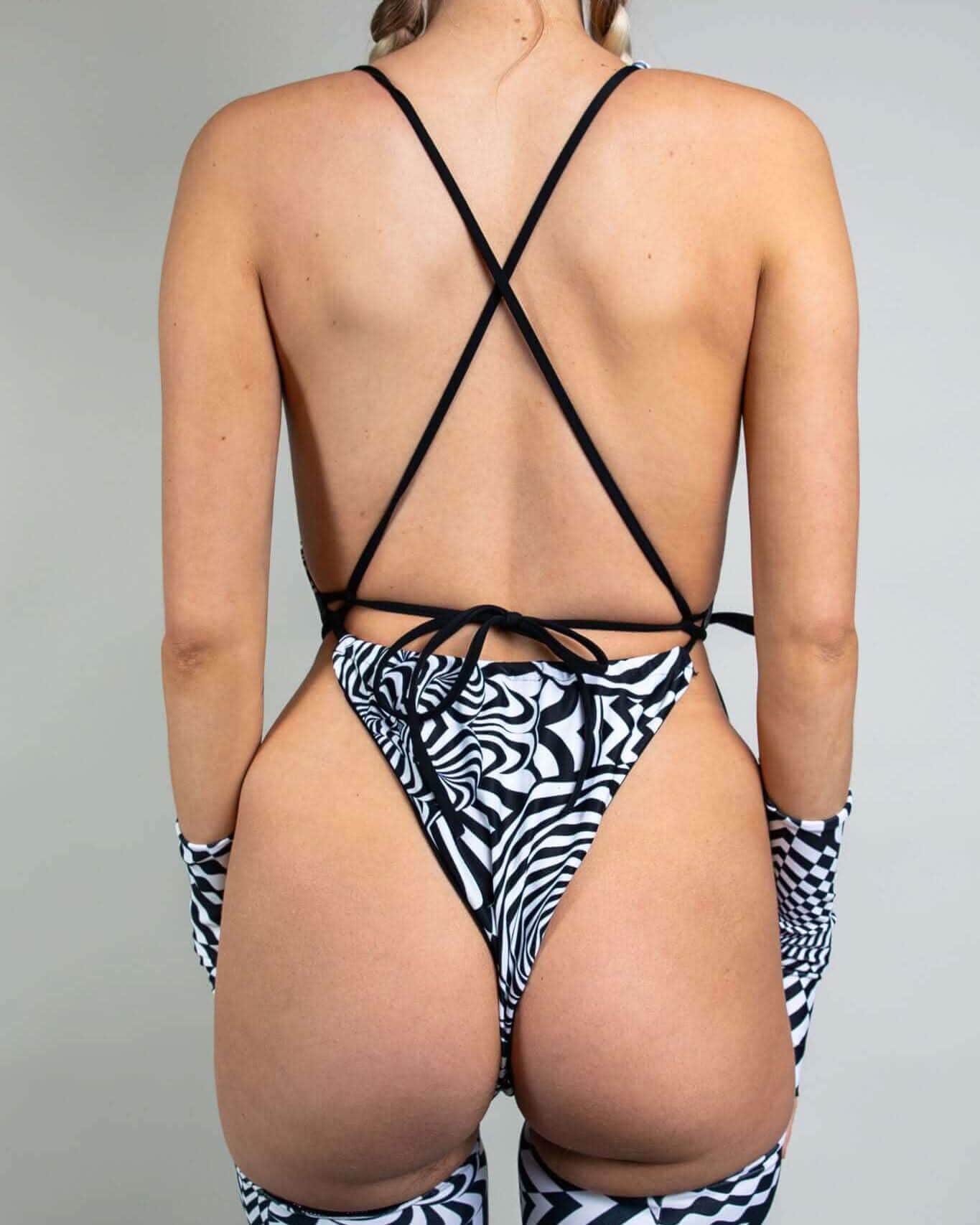 Back view of Distortion black white geometric rave bodysuit with criss-cross straps and matching sleeves