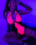 Hot pink rave bodysuit with black O-ring details and fishnet sleeves under UV festival lighting