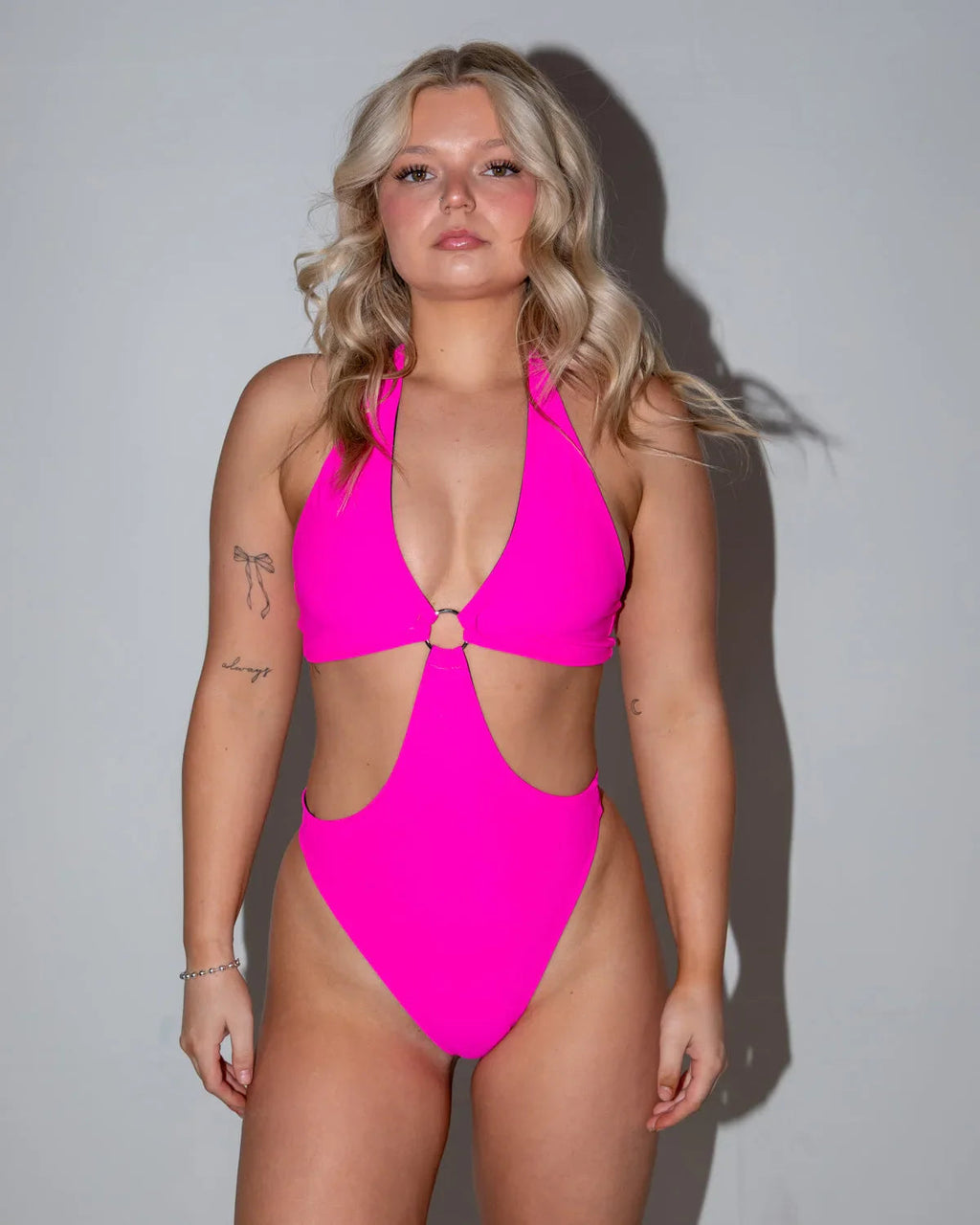 Model in a hot pink O-ring bodysuit, featuring a halter neck and side cutouts, perfect for a rave festival.