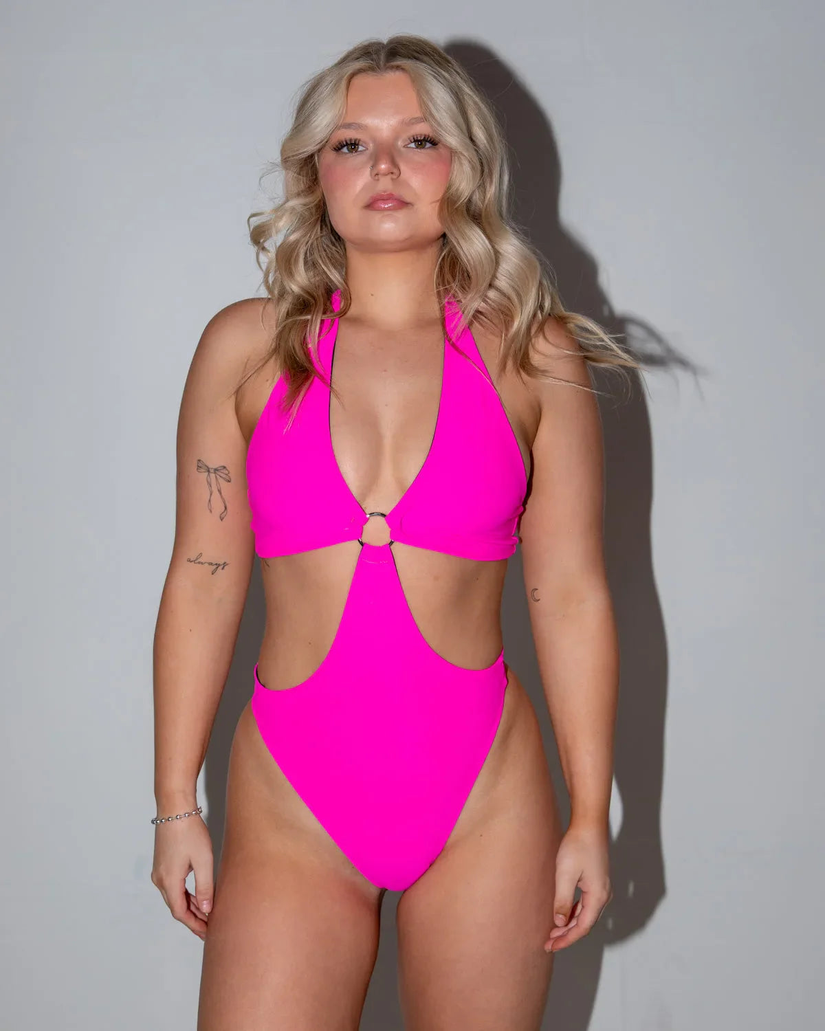 Model in a hot pink O-ring bodysuit, featuring a halter neck and side cutouts, perfect for a rave festival.