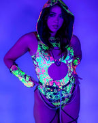 Woman modeling Intensity rave bodysuit with keyhole cutout and leg straps under blacklight festival lighting