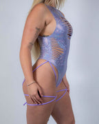 Side view of lavender holo rave bodysuit with sideboob cutouts and leg straps for festival wear