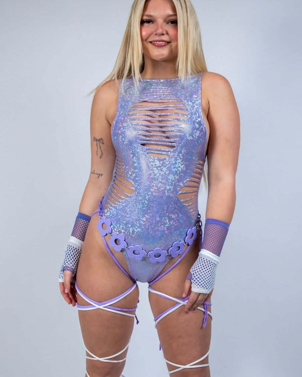 Blonde model wearing lavender holographic rave bodysuit with sideboob cutouts and white leg straps front view