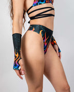 Blaze High Waisted Thong and matching arm sleeves shown from the side, featuring a vibrant flame pattern with teal speckles, perfect for rave festivals.