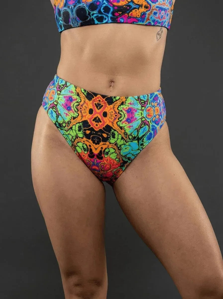 Lucidity High Waisted Brazilian Bottoms in a vibrant psychedelic rainbow pattern, shown from the front on a model, perfect for rave festivals.