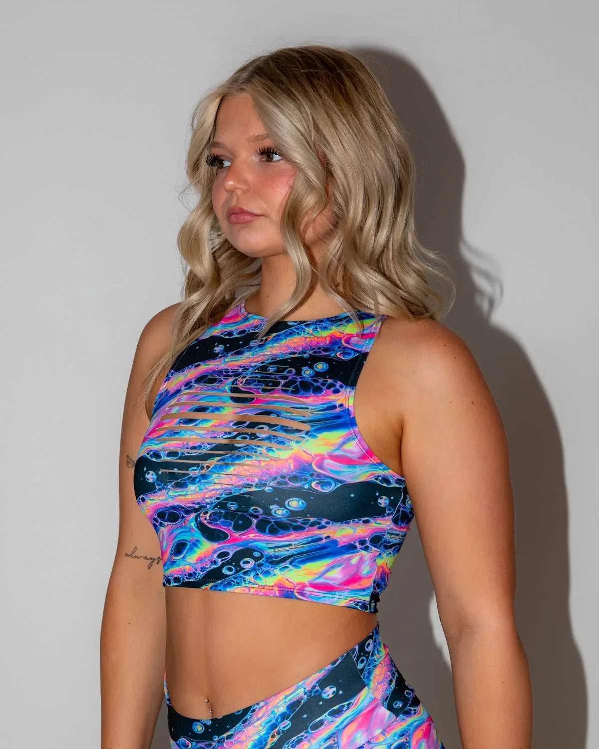 Acid Sky Slit Crop Top in multi-color, modeled from the side, showcasing the vibrant psychedelic rave pattern and chest slits.