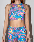 Groovy Slit Crop Top and matching leggings on a model, front view, showcasing the vibrant psychedelic pattern with peace signs, smiley faces, and rainbows, perfect for rave festivals.