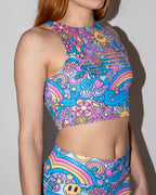 Side view of a model wearing the Groovy Slit Crop Top, showcasing its vibrant psychedelic pattern with rainbows and peace signs, perfect for a festival.