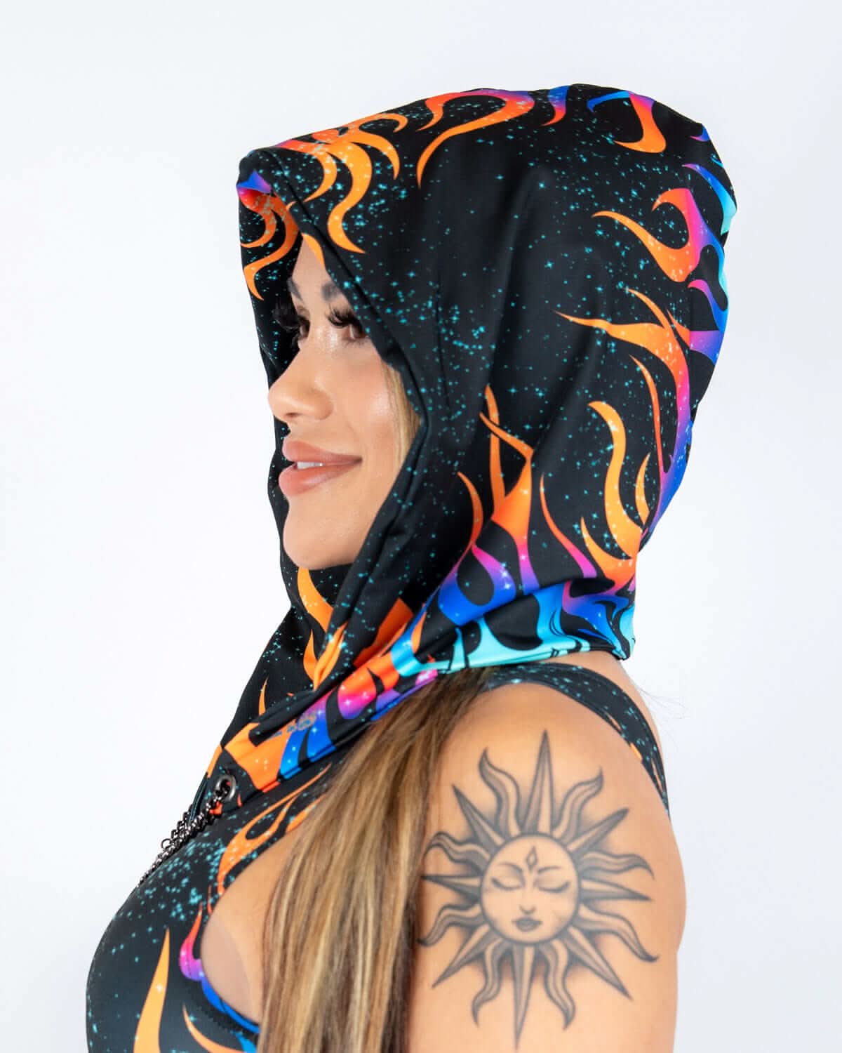 Blaze Assassin Hood in black with neon flame graphics, worn by a woman from the side, perfect for rave festivals.