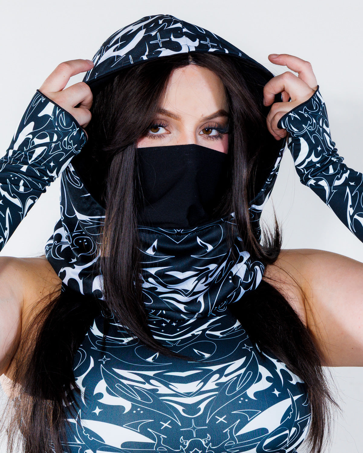 BLVDE Warrior Hood in black and white, worn by a woman facing front, showcasing the cosmic marble swirls and celestial motifs, perfect for a rave festival.