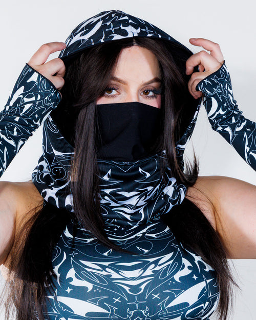 BLVDE Warrior Hood in black and white, worn by a woman facing front, showcasing the cosmic marble swirls and celestial motifs, perfect for a rave festival.