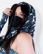The BLVDE Warrior Hood in black and white, worn by a model from the front, featuring cosmic marble swirls and celestial motifs, perfect for a rave festival.