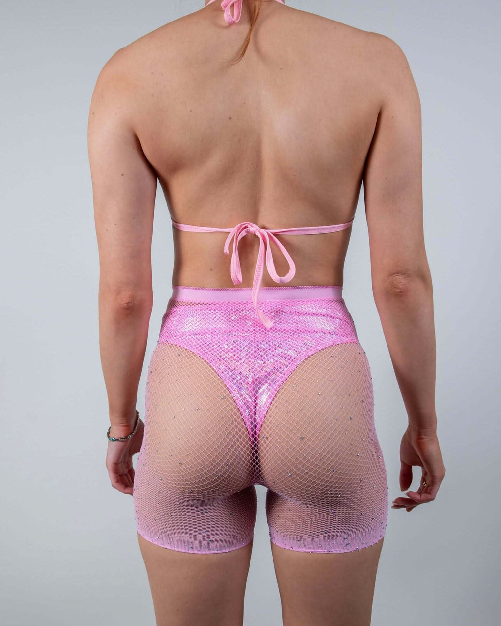Back view of the Bikini Babe Rhinestone 2 Piece Fishnet Set in pink, showcasing the halter top and high-waisted biker shorts, perfect for a rave festival.