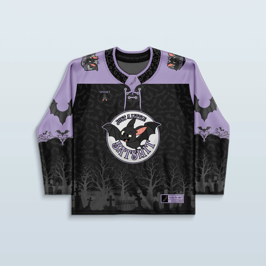 Front view of the Batshit Hockey Jersey, a limited edition rave top in lavender and black, featuring a cartoon bat crest and a haunted graveyard design.