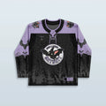 Front view of the Batshit Hockey Jersey, a limited edition rave top in lavender and black, featuring a cartoon bat crest and a haunted graveyard design.