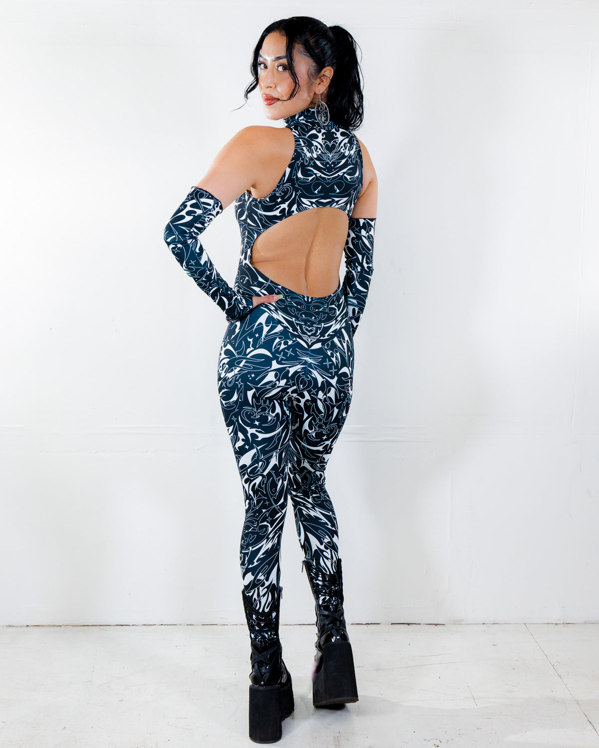 BLVDE Cold Shoulder Jumpsuit in black and white marble swirl print, seen from the back, featuring a large cutout for a striking rave festival look.