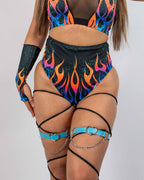 Model wearing Blaze high waisted rave pants with colorful flame print and black leg harnesses front view