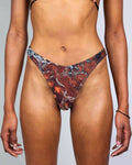 Fossil Risk rave pants bikini bottoms in rust red fossil print, front view festival outfit