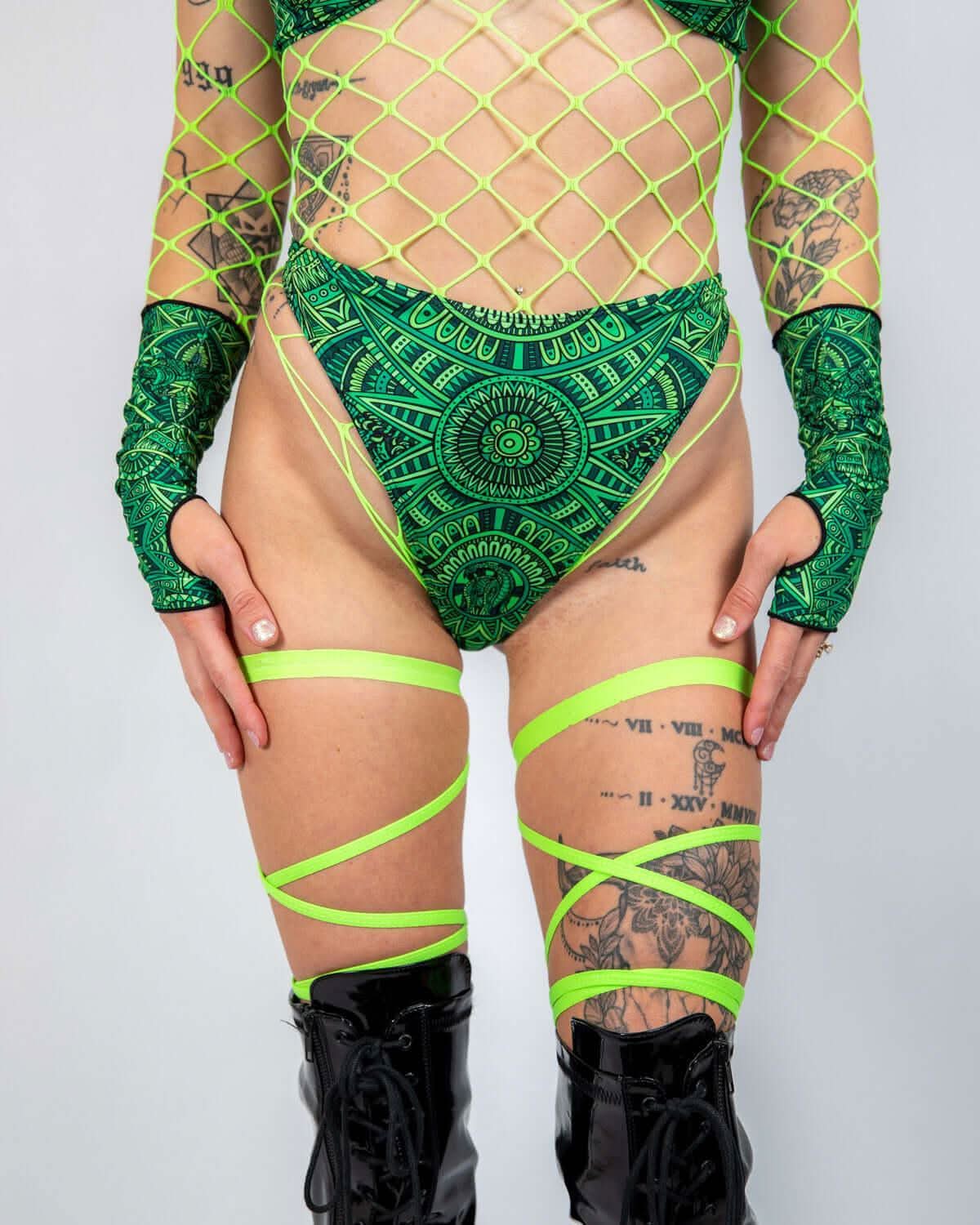 Green Dominion tribal print rave pants with neon fishnet overlay modeled front view festival outfit