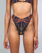 Magma retro thong rave pants with fiery lava print - black base with orange yellow veining front view