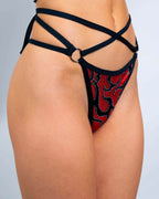 Red flame print rave pants with black strappy O-ring cut-out design modeled from front angle