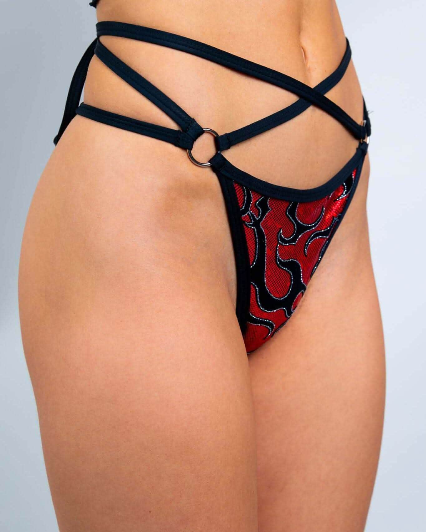 Red flame print rave pants with black strappy O-ring cut-out design modeled from front angle