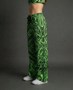 Model wearing Techtronix Lucy Pants, side view, showcasing the acid green and black angular circuit print, perfect for rave festivals.
