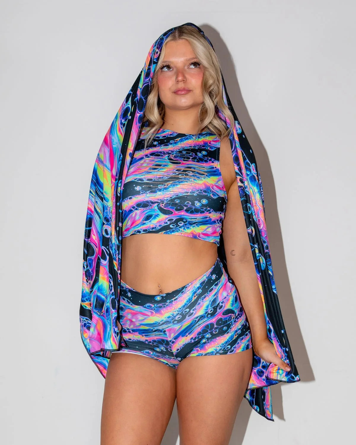 Acid Sky Festival Scarf draped over a blonde model, showcasing the vibrant psychedelic pattern from the front. Perfect rave accessory.