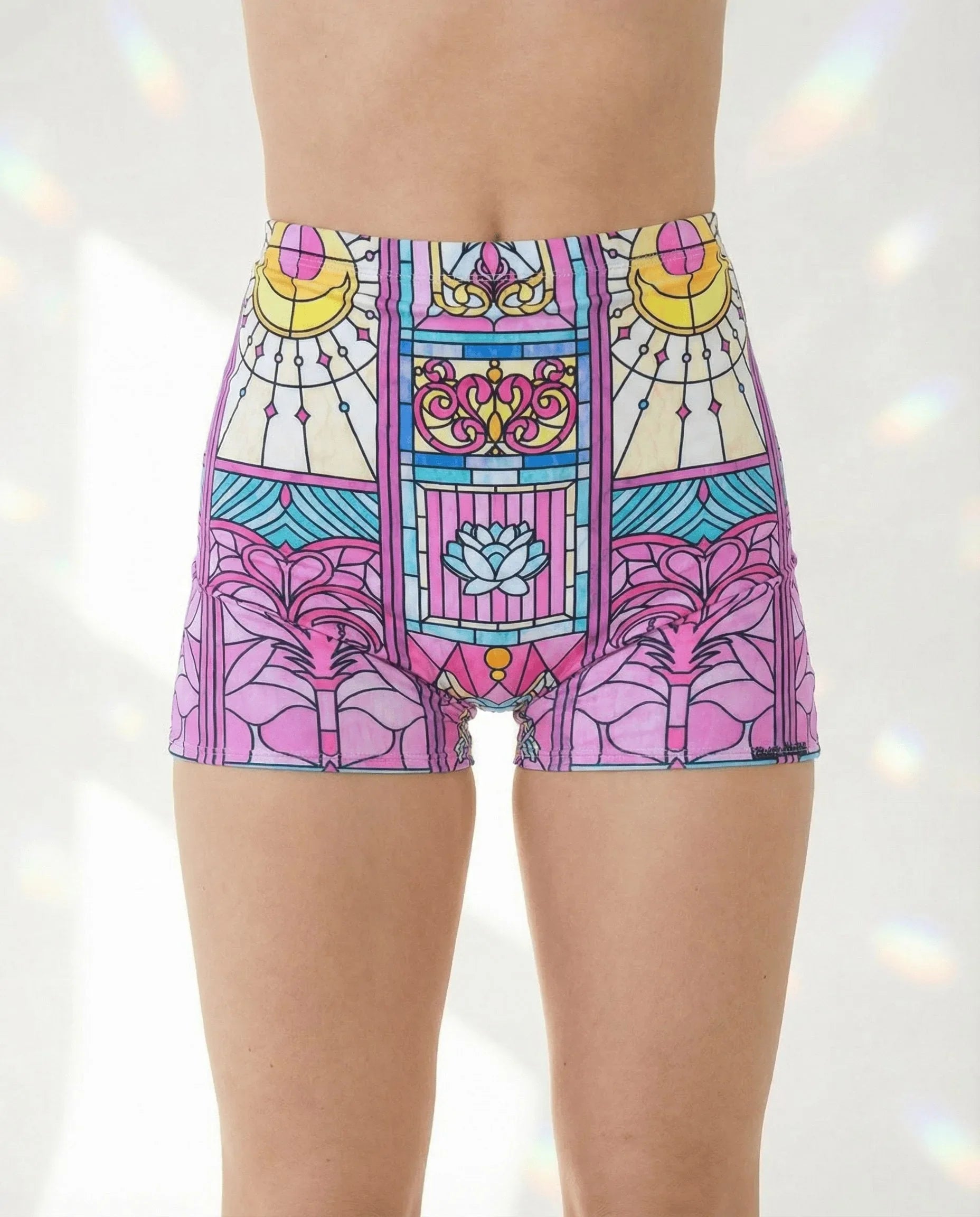 Moonlight High Waist Shorts in a pastel stained-glass pattern, featuring crescent moons and a blue lotus, modeled from the front for a rave festival look.