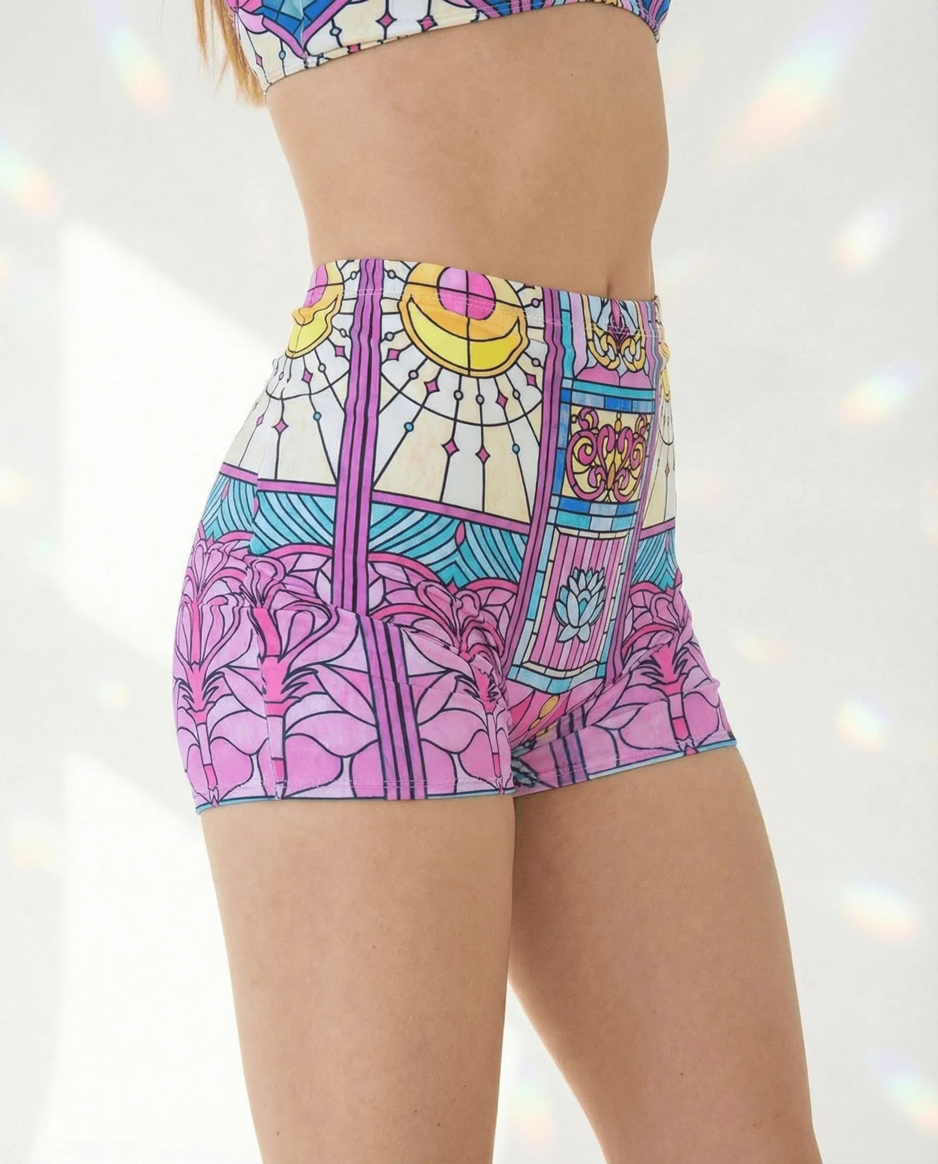 Moonlight High Waist Shorts from the side, featuring a vibrant pink, teal, and yellow stained-glass rave print.