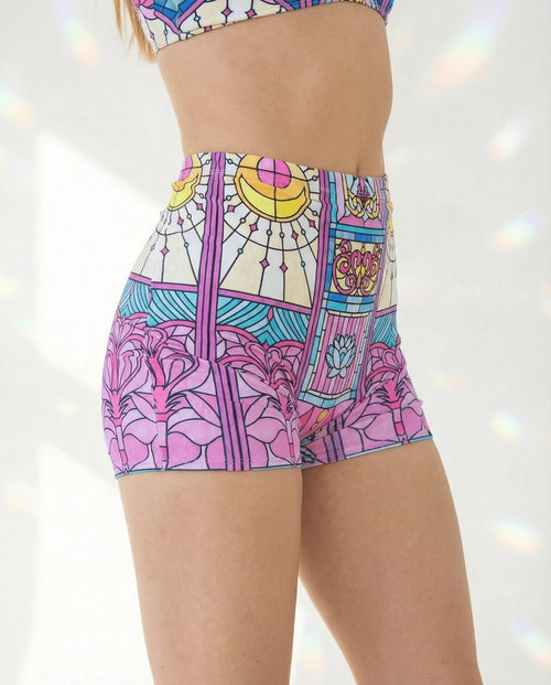 Moonlight High Waist Shorts from the side, featuring a vibrant pink, teal, and yellow stained-glass rave print.