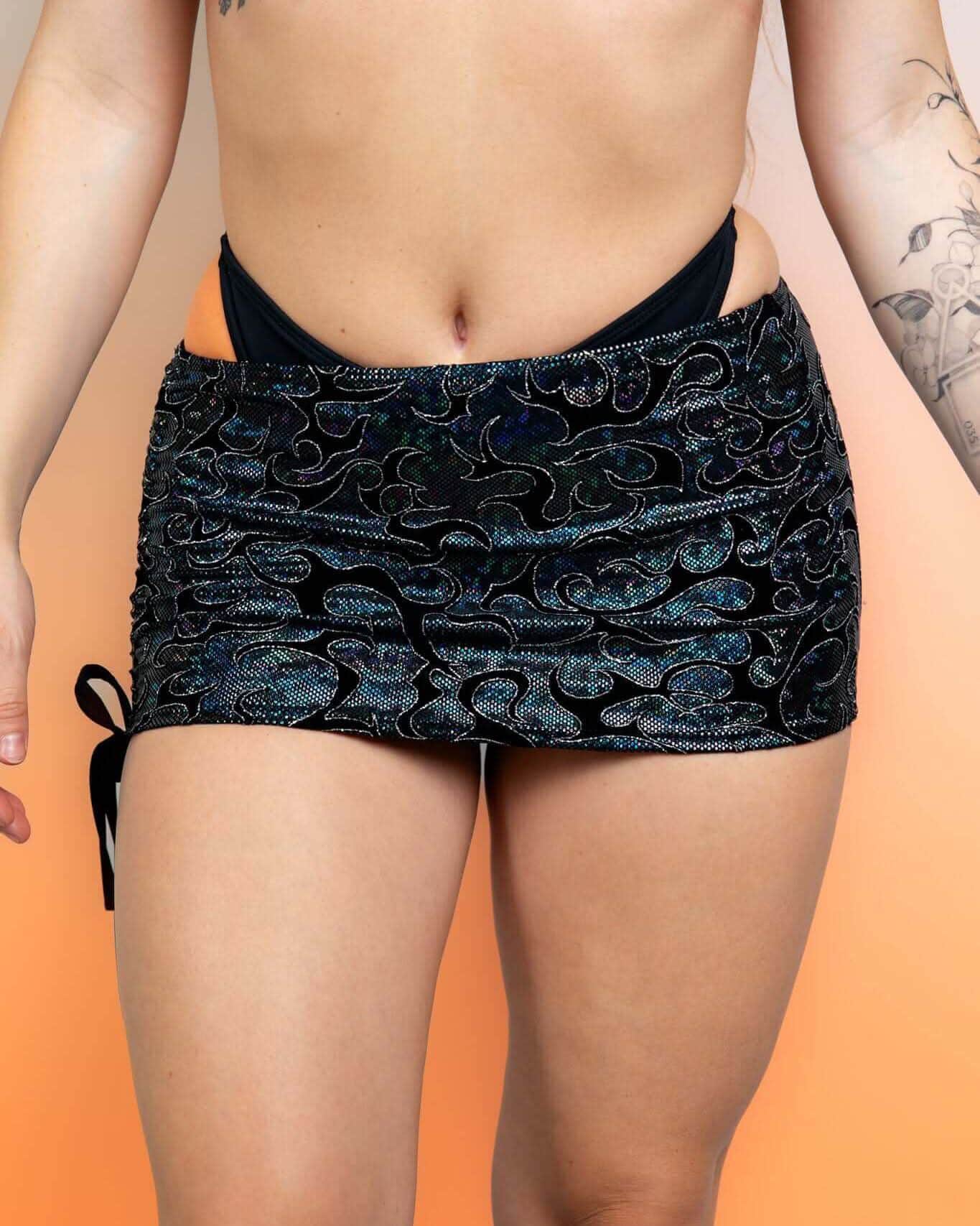 Black holographic rave skirt with iridescent swirl pattern and side cinch ties modeled from front
