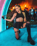 Model wearing black mesh swirl rave skirt with crop top at festival with neon lighting