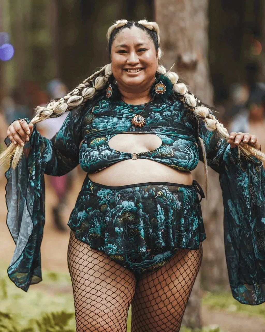 Plus-size model wearing Faewood Mesh Swirl Skirt and matching top, posing frontally at a rave festival.