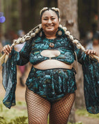 Plus-size model wearing Faewood Mesh Swirl Skirt and matching top, posing frontally at a rave festival.