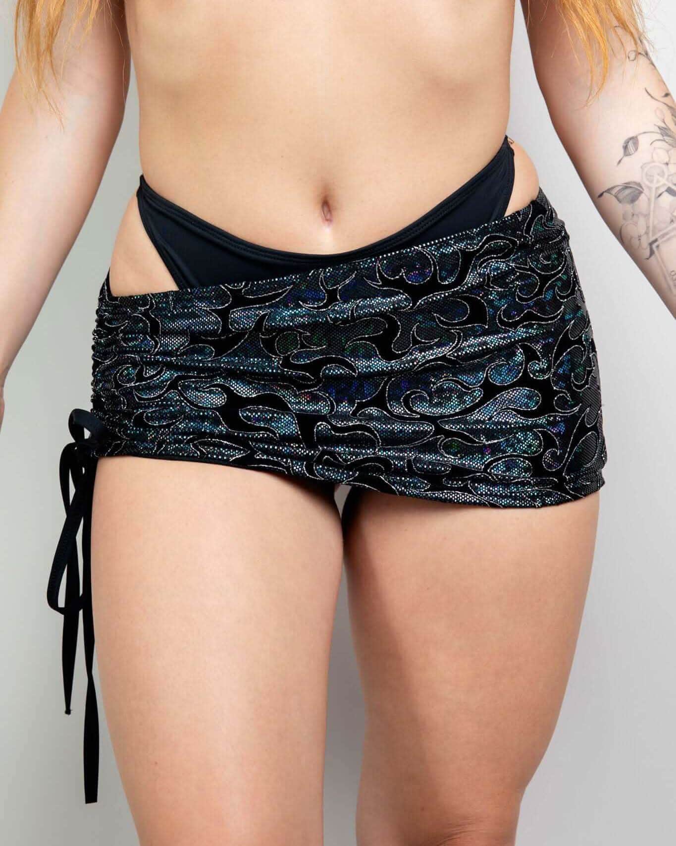 Black iridescent Hellcat rave skirt with side cinch ties modeled from front view for festival outfits