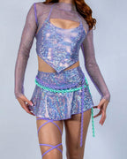 Lavender holographic rave skirt styled with matching crop top and mesh overlay on model front view