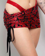 Red flame print rave skirt with adjustable drawcord ties shown from side angle on model