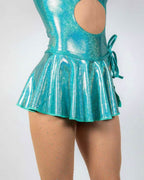 Teal sparkle swirl rave skirt detail showing holographic pleated hem and wrap tie styling on model
