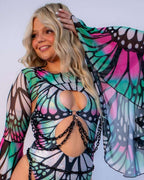 A woman models Flutter Mesh Bell Sleeves, showcasing the pink and teal butterfly pattern and sheer fabric, perfect for a rave festival.