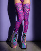 Vanish Leg Sleeves in neon pink and purple psychedelic pattern, worn with iridescent platform boots, perfect for rave festivals.