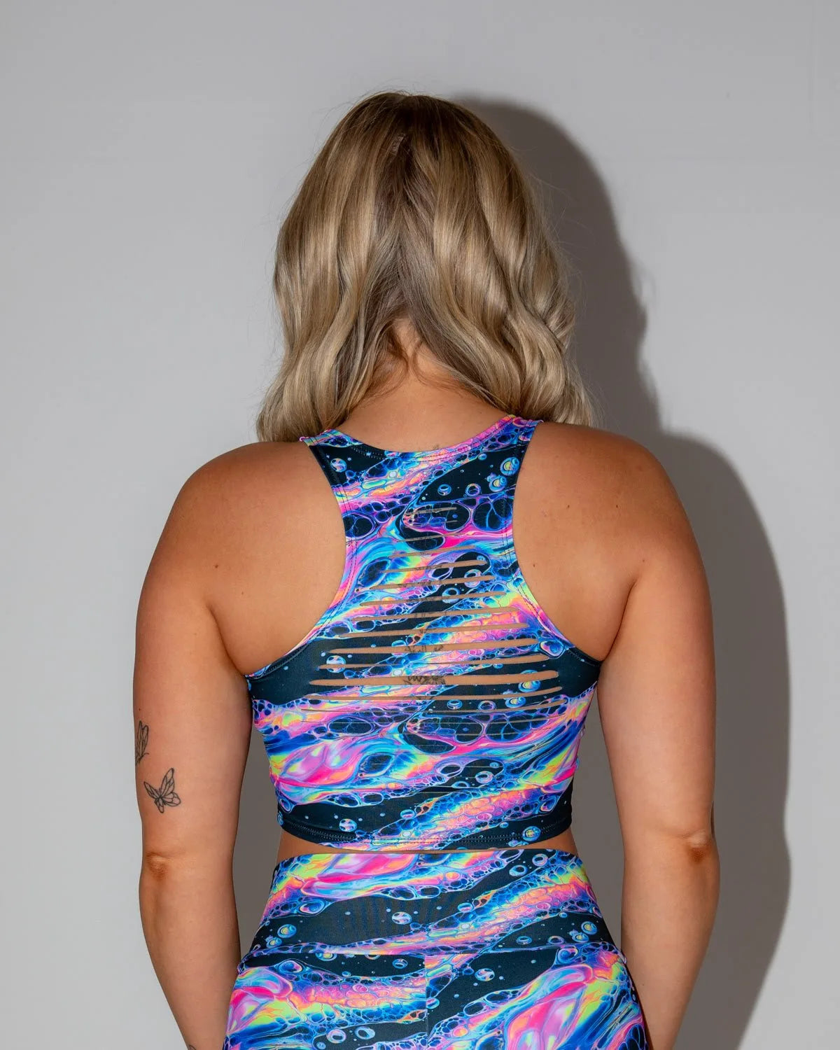 Acid Sky Slit Crop Top seen from the back, showcasing vibrant psychedelic colors and horizontal slits, perfect for a rave festival.