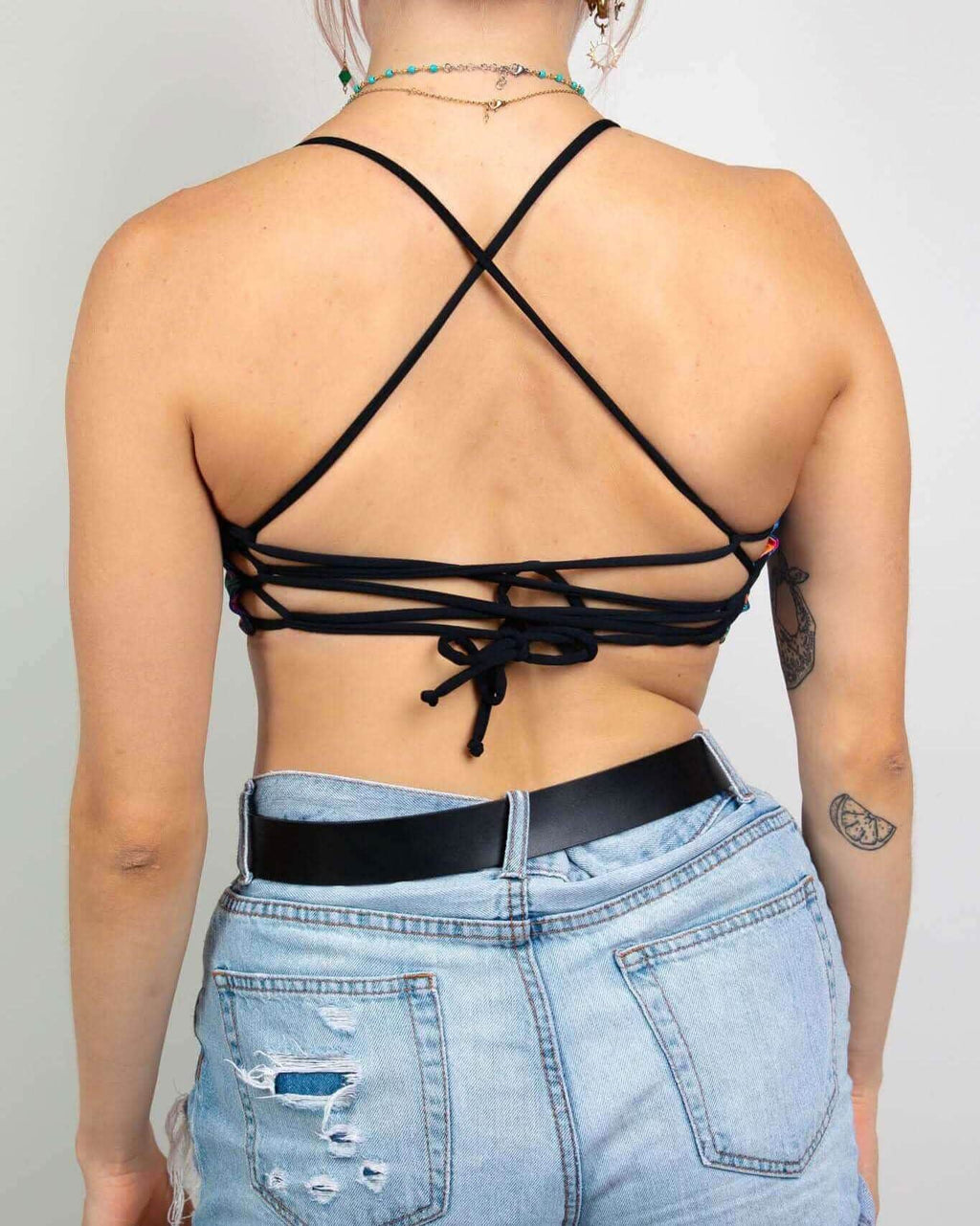 Back view of black Saurian reversible rave top with crossed strappy design and lace-up detail for festival outfits