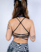 Back view of black strappy rave top with crisscross lace-up design, paired with Meltdown print festival bottoms and cat ears