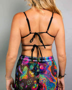 Back view of black strappy rave top with tie closures worn with colorful Vivid Shroomie psychedelic festival outfit