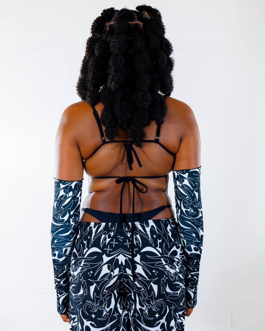 BLVDE Wonder Top shown from the back, featuring a black tie-back bikini top and matching patterned sleeves, perfect for a rave festival.